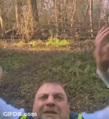 A Police Officer Wearing A Yellow Vest And Tie Is Yawning . GIF