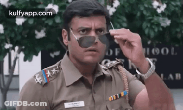 A Police Officer Wearing Sunglasses Is Making A Funny Face . GIF