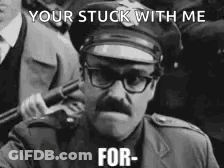 A Police Officer With Glasses And A Mustache Is Holding A Gun In A Black And White Photo . GIF