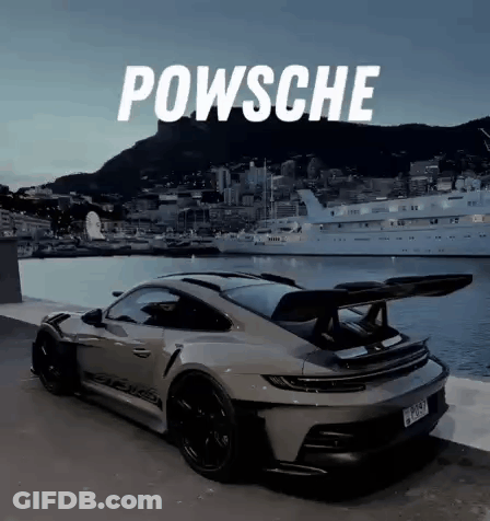 A Porsche Is Parked Next To A Body Of Water With A Boat In The Background . GIF