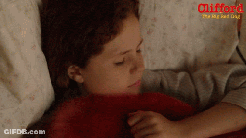 A Poster For Clifford The Big Red Dog Shows A Young Girl Laying In Bed GIF