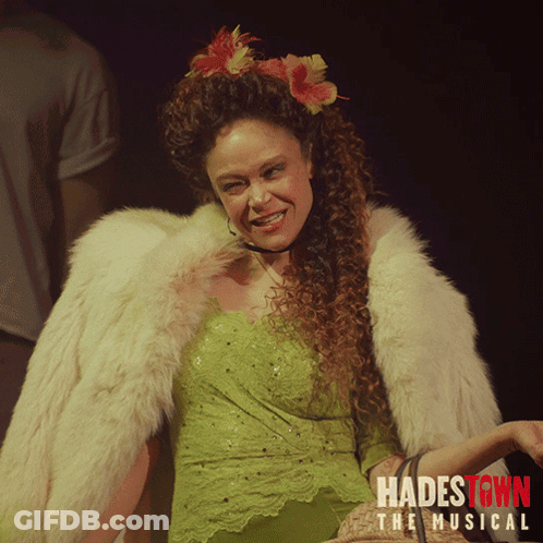 A Poster For Hadestown The Musical Shows A Woman In A Green Dress And Fur Coat GIF