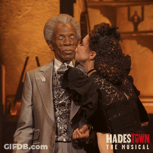 A Poster For Hadestown The Musical Shows A Woman Kissing An Old Man On The Cheek GIF