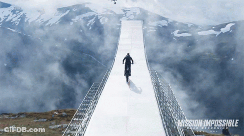 A Poster For Mission Impossible Shows A Man Riding A Motorcycle Over A Bridge GIF