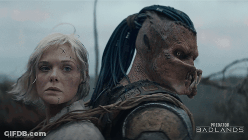 A Poster For Predator Badlands Features A Woman And A Monster GIF