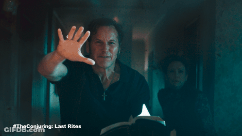 A Poster For The Conjuring Last Rites With A Man Holding A Book GIF
