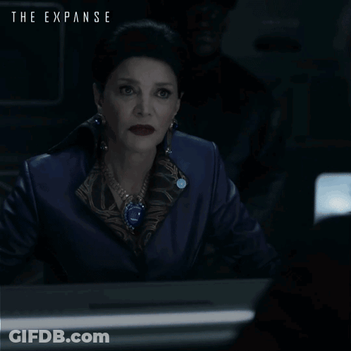 A Poster For The Expanse Shows A Woman Sitting At A Desk GIF