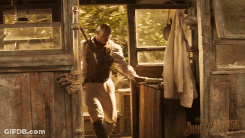 A Poster For The Jungle Cruise Shows A Man Holding A Rifle GIF
