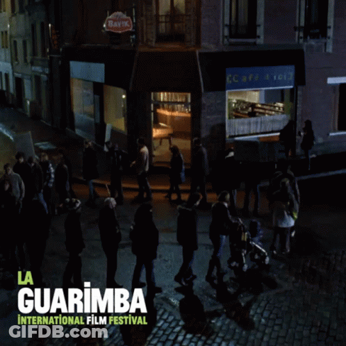 A Poster For The La Guarimba International Film Festival Shows A Group Of People Walking Down A Cobblestone Street GIF