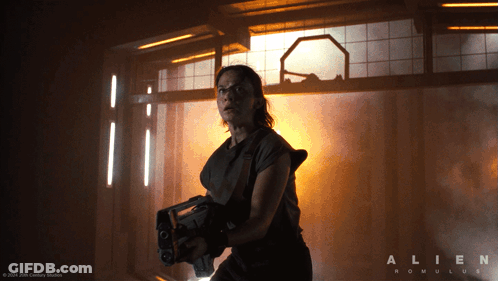 A Poster For The Movie Alien Romulus With A Woman Holding A Gun GIF
