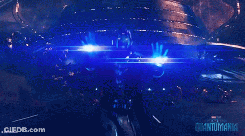 A Poster For The Movie Quantumania Shows A Person Holding A Beam Of Light GIF