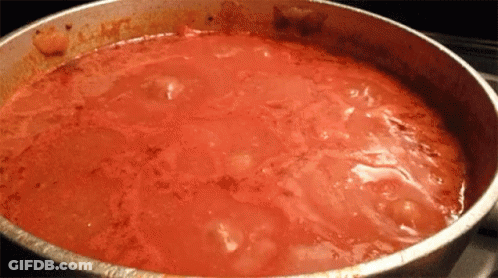A Pot Of Tomato Sauce Is Being Cooked On The Stove GIF