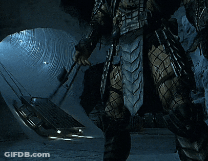A Predator Is Standing In A Tunnel Holding A Spear GIF