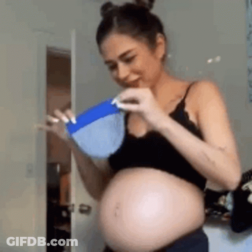 A Pregnant Woman In A Black Top Is Holding A Blue Bowl . GIF