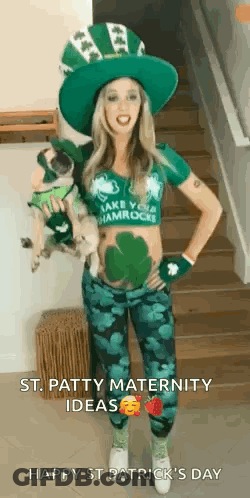 A Pregnant Woman In A Leprechaun Costume Is Standing On A Set Of Stairs Holding A Dog . GIF