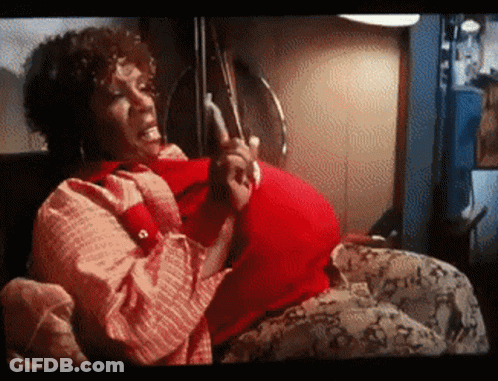 A Pregnant Woman Is Sitting On A Couch Holding Her Belly GIF