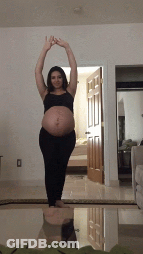 A Pregnant Woman Stretches Her Arms Over Her Head GIF