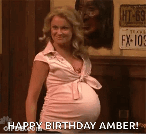 A Pregnant Woman With A Big Belly Is Standing In Front Of A Wall And Says `` Happy Birthday Amber '' . GIF
