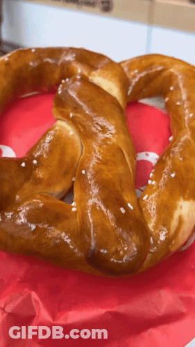 A Pretzel Is Sitting On A Red Napkin With A White S On It GIF