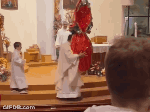 A Priest Holds A Large Red Easter Egg In His Hands GIF