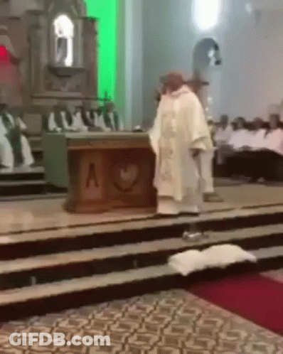 A Priest In A White Robe Stands In Front Of An Altar With A Heart On It GIF
