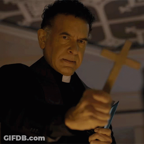 A Priest Is Holding A Knife In Front Of A Wooden Cross GIF
