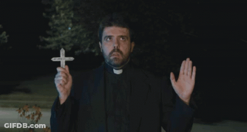 A Priest Is Holding A Small Cross In His Hands GIF