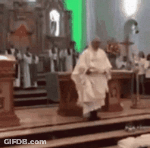 A Priest Is Walking Down The Aisle Of A Church With A Green Light Behind Him . GIF