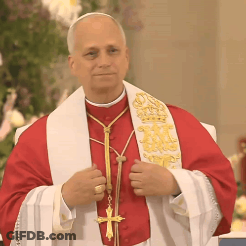 A Priest Wearing A Red Robe And White Stole With A Cross On It GIF