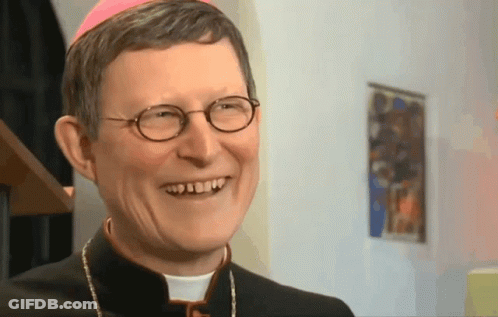 A Priest With Glasses And A Pink Hat Smiles GIF