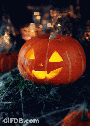 A Pumpkin With A Face Carved Into It Is Lit Up In The Dark GIF