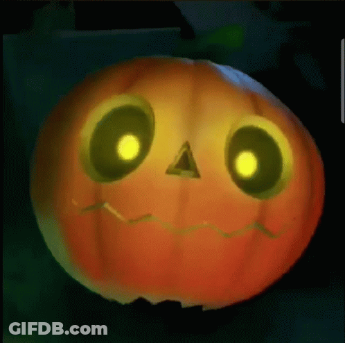 A Pumpkin With Glowing Eyes And A Face Carved Into It Is Sitting On A Table . GIF