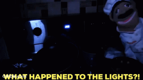 A Puppet In A Chef Costume Is Standing In A Dark Room With The Words What Happened To The Lights Written Below It GIF