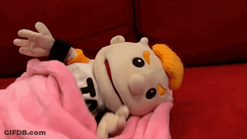 A Puppet Is Laying On A Couch With A Pink Blanket . GIF