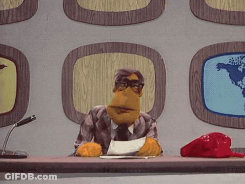 A Puppet Is Sitting At A Desk With A Microphone GIF