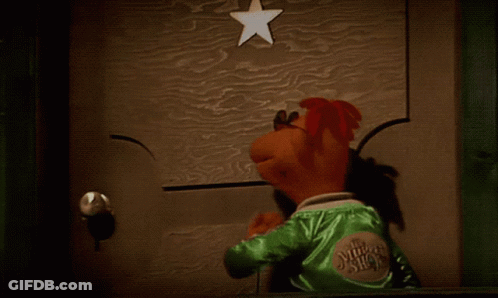 A Puppet Is Standing In Front Of A Door With A Star Above It GIF