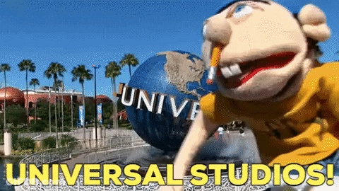 A Puppet Is Standing In Front Of A Giant Globe That Says Universal Studios On It GIF