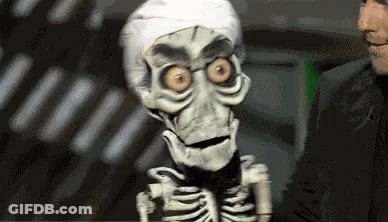 A Puppet Of A Skeleton Is Standing Next To A Man In A Suit . GIF