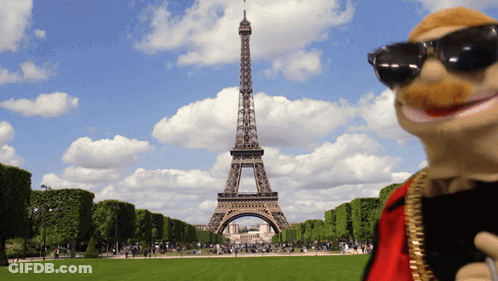 A Puppet Stands In Front Of The Eiffel Tower In Paris GIF