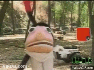 A Puppet With A Bird 'S Head Is Standing Next To A Golf Cart In A Forest . GIF
