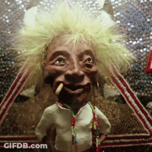 A Puppet With A Cigarette In His Mouth Is Wearing A White Shirt And Necklaces GIF