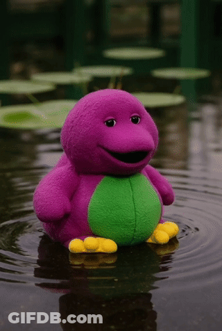 A Purple And Green Barney Stuffed Animal Is Floating In The Water GIF