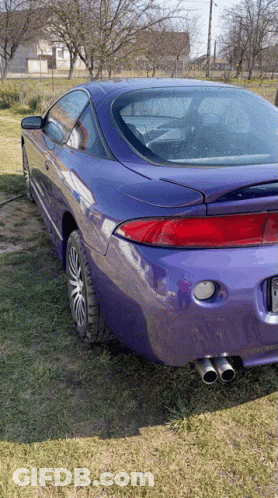 A Purple Car Is Parked In A Grassy Field With Trees In The Background GIF