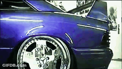A Purple Car With Chrome Wheels And A Mercedes Logo On The Front GIF