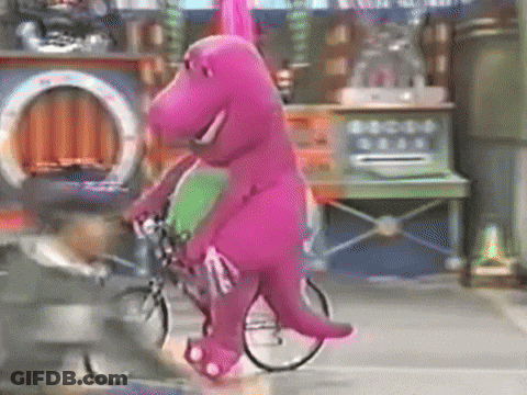 A Purple Dinosaur Is Riding A Bike On A City Street GIF