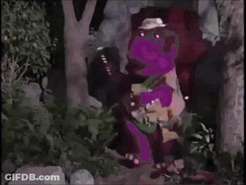 A Purple Dinosaur Is Standing In A Forest Wearing A Hat . GIF