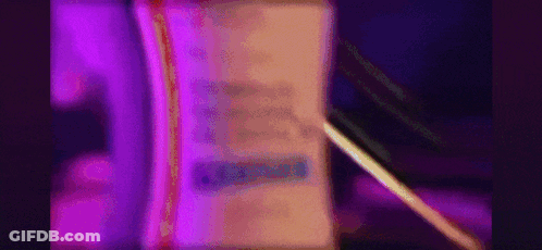 A Purple Light Is Shining On A Book With A Pen . GIF