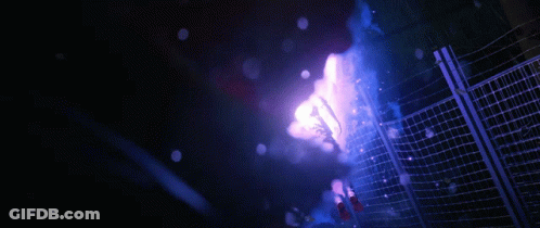 A Purple Light Is Shining Through A Fence In The Dark GIF