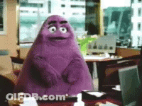 A Purple Monster Is Sitting At A Desk In An Office GIF
