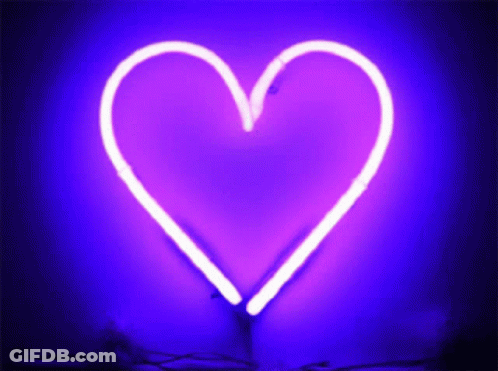 A Purple Neon Heart Is Lit Up On A Dark Purple Background GIF